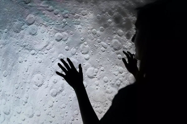 An astronaut looks at the surface of the moon from the craft